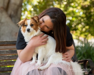 woman-sitting-on-park-bench-hugging-small-white-fluffy-dog