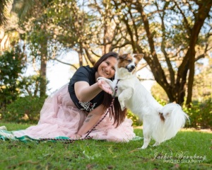 woman-wearing-pink-frilly-dress-playing-with-small-fluffy-dog-in-park