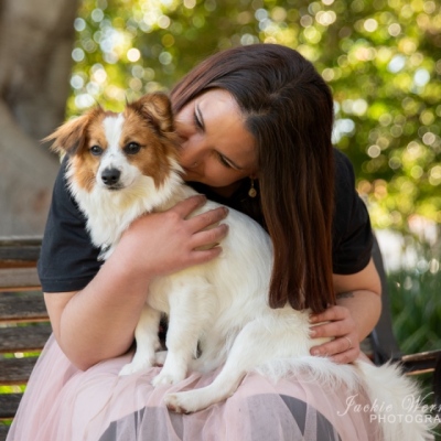 woman-sitting-on-park-bench-hugging-small-white-fluffy-dog