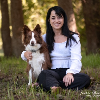brown-and-white-bordercollie-sitting-with-pretty-woman-under-trees