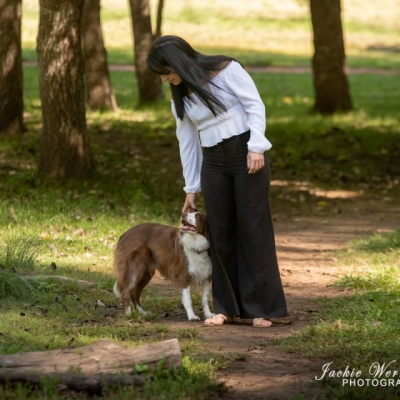 brown-and-white-bordercollie-standing-with-pretty-lady-on-shady-path